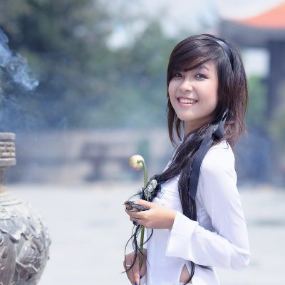 老奶奶编辑部内容复核员阿棠的工作照：年轻女性戴着细框眼镜对着双屏核对条目，屏幕上是排布整齐的分类表格，桌面一杯放凉的茶，安静专注